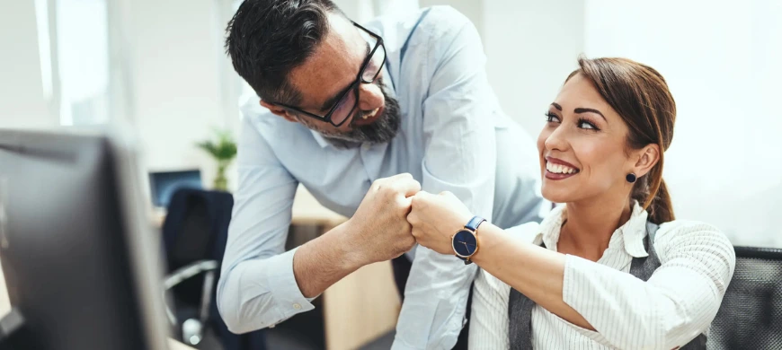 man and woman cheering in office